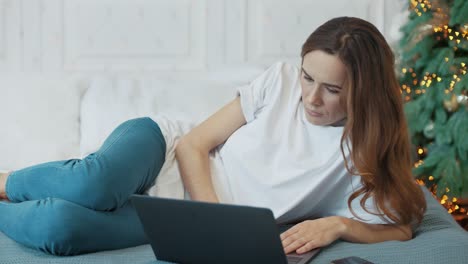 Konzentrierte,-Legere-Frau,-Die-Mit-Einem-Laptop-Im-Schlafzimmer-Liegt.