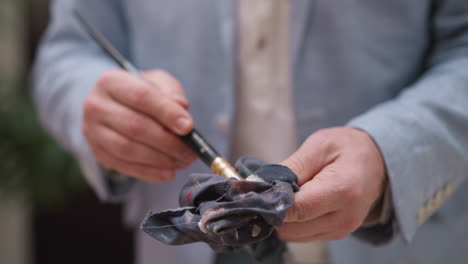 man artist wipes excess paint from brush. skilled painter demonstrates disciplined approach to maintaining paint tools. quality of artistic tools