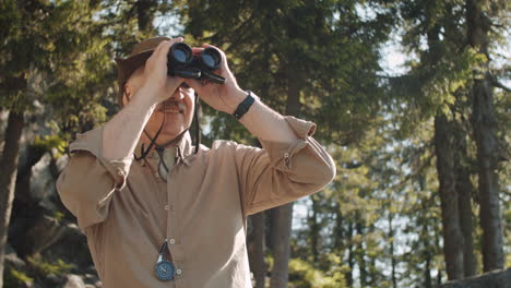 hombre mayor observando la naturaleza con binoculares en el bosque