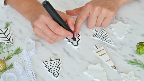 female hands decorate ornaments with pine tree shape using a marker pen