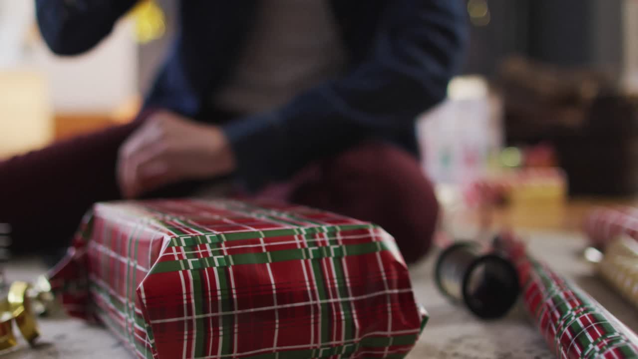 sección media de la mujer envolviendo regalos de navidad en casa