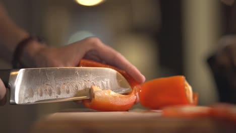 quitando las semillas de un pimiento rojo con un cuchillo afilado sobre la tabla de madera
