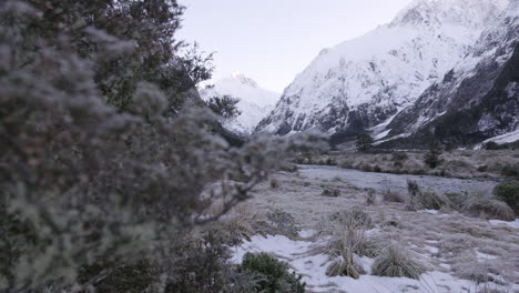 reveal shot of running river in a valley surrounded by snow capped peaks and mountains in winter, new zealand