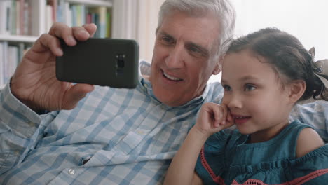 Abuelo-Y-Niño-Teniendo-Video-Chat-Usando-Teléfono-Inteligente-Niña-Compartiendo-Fin-De-Semana-De-Vacaciones-Con-La-Familia-Abuelo-Disfrutando-Charlando-Sobre-Tecnología-Móvil-En-Casa-Con-Nieta