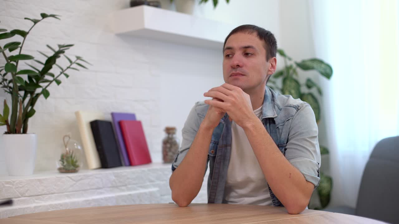 joven pensativo y serio estudiante escritor sentado en el escritorio de la oficina de casa con una computadora portátil pensando en la inspiración búsqueda de soluciones a problemas ideas perdidas en pensamientos concepto soñando mirando hacia otro lado