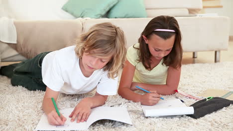 brother and sister doing homework on the living room floor