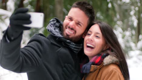 couple talking and taking a selfie with mobile phone on a winter day