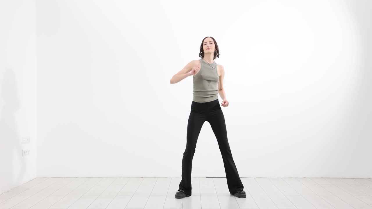 Ung kvinde danser energisk i et hvidt studie