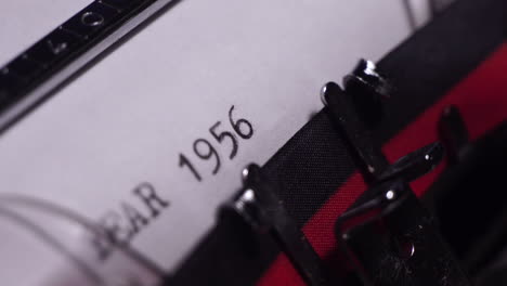 year 1956, typing on white paper in vintage typewriter, close up