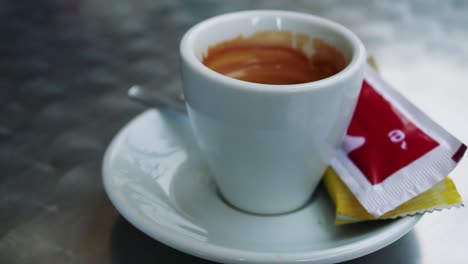 a white cup of coffe in a metal table on a cloudy day