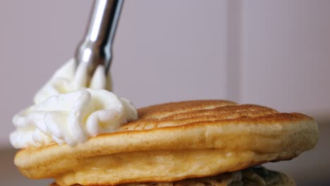 Static-slow-motion-shot-of-delicious-pancakes-while-a-cream-dispenser-sprays-delicious-whipped-cream-on-top-for-a-sweet-dessert