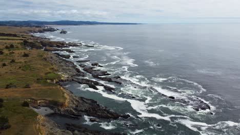 4K-30FPS-Aerial-Footage-Oregon-Coast---Flying-footage-over-a-coastal-shore,-natural-fjords,-pacific-northwest-forest,-ocean-waves-crash-against-rocky-shore,-seaside-lagoons-and-beach