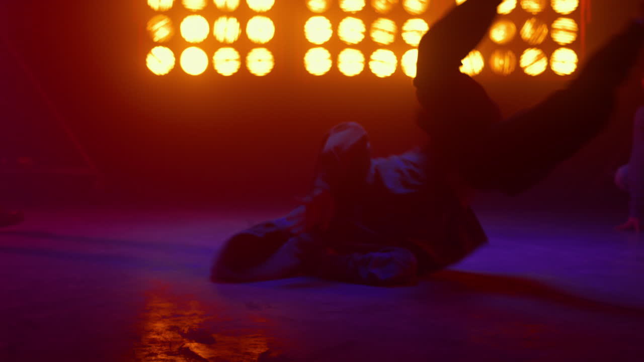Strong guy performing windmill spinning on back indoors. Dancer showing tricks.