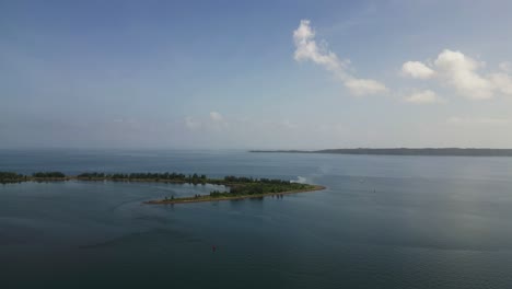 scenic aerial view of curved, uninhabited islet in the middle of philippine bay, bicol during daytime.