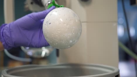 Scientist-with-purple-safety-gloves-wiping-a-bulb-during-an-experiment