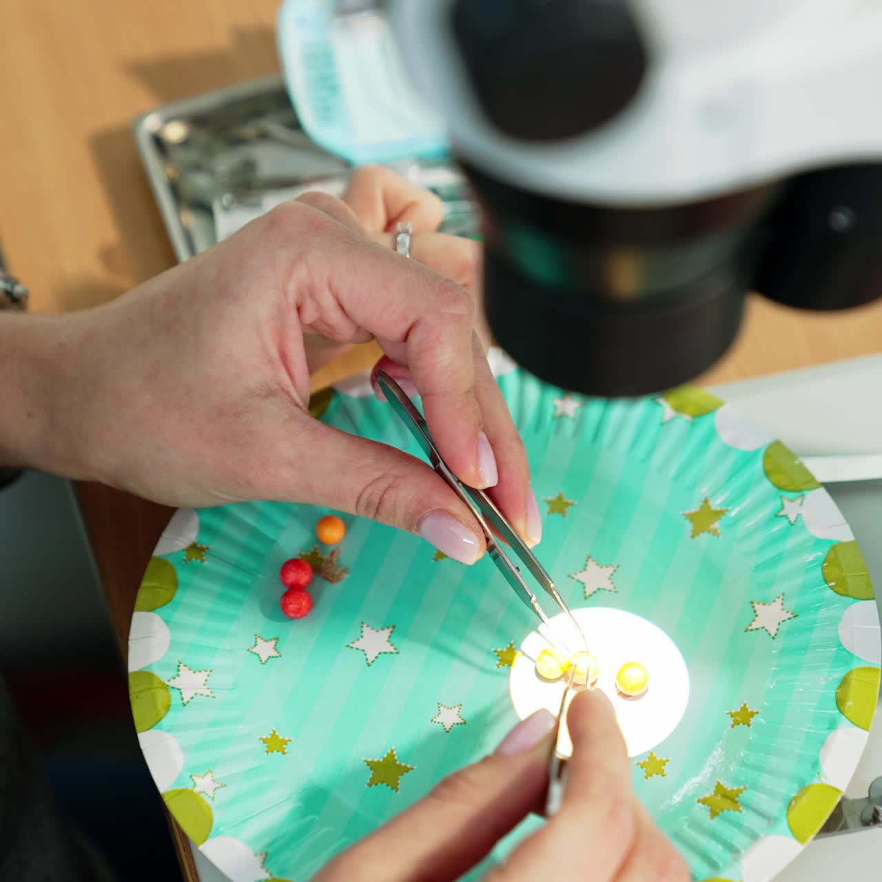 Female hands holding forceps and use them to move beads. Medical students studying ophthalmology course and practicing