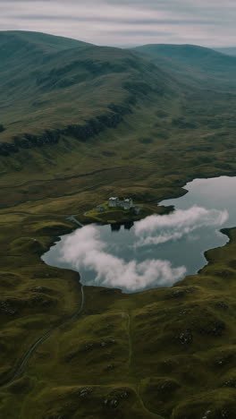 Aerial view of a Scottish loch and castle nestled in a valley with surrounding mountains