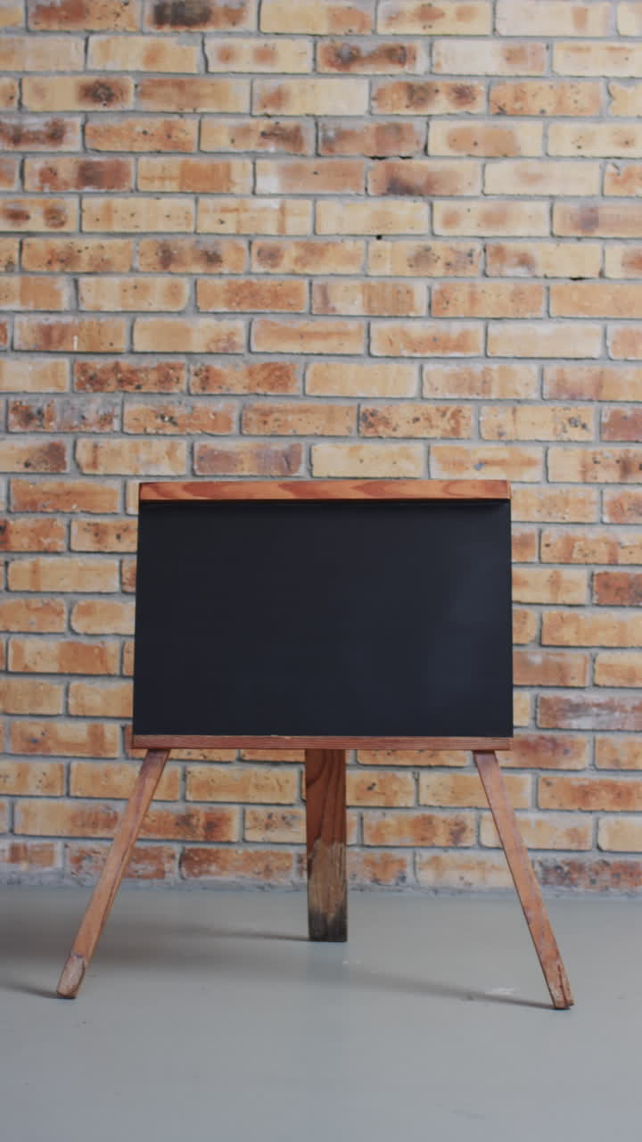 Vertical video of blackboard sign with copy space on wooden stand and brick wall background