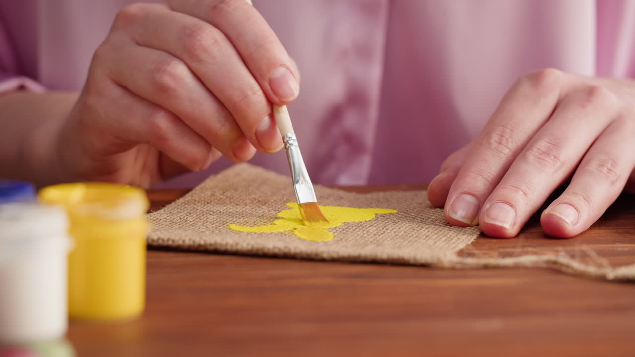Close-up van Handen die een Geel Ontwerp Schilderen op Jute Stof