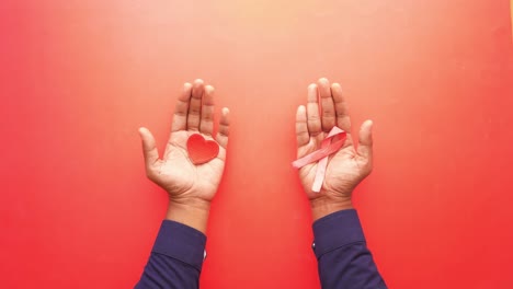 manos sosteniendo corazones y cintas rosas para concienciar sobre el cáncer de mama