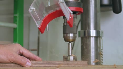carpintero usando un taladro de columna para hacer un agujero en un bloque de madera a cámara lenta de 100 fps