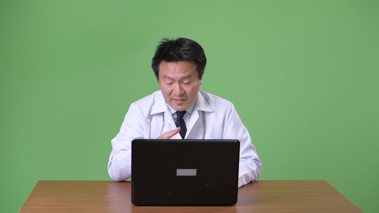 성숙한 일본인 남성, 초록색 배경의 의사