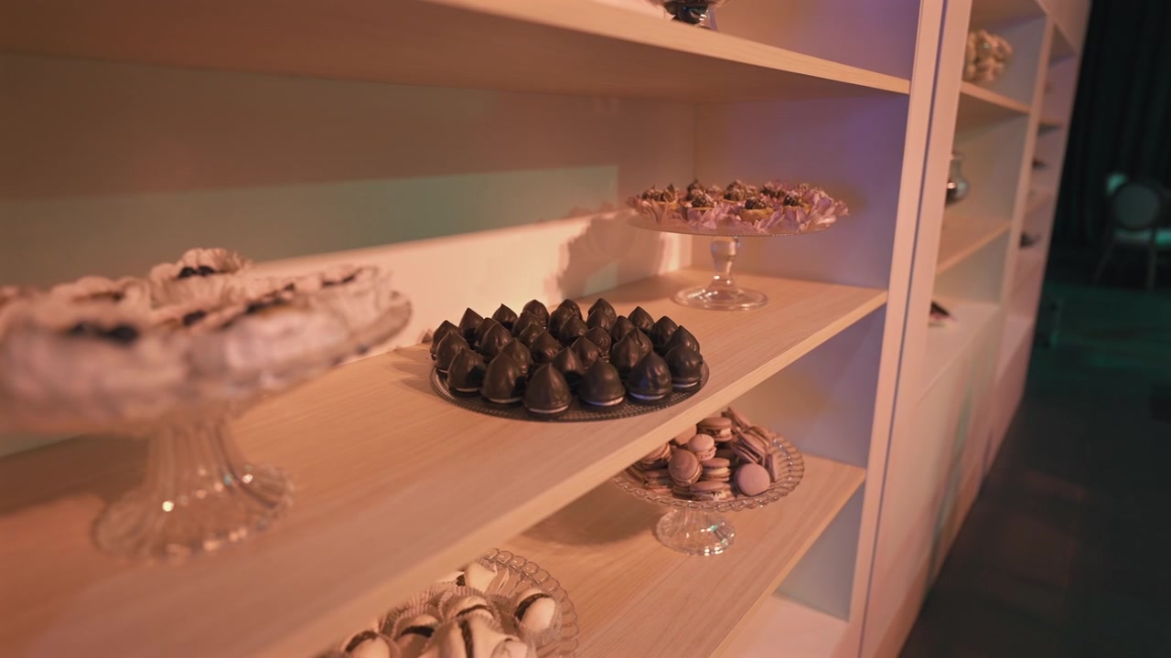 Dolci assortiti elegantemente disposti su alzate di vetro a più livelli a un evento sofisticato. Ideale per blog culinari o promozioni di pianificazione eventi.