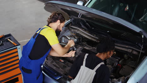 los trabajadores del taller de reparación arreglan el coche con alicates