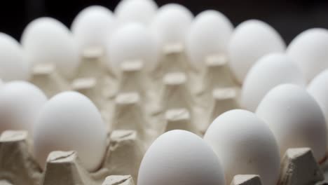 close view of a farmer taking eggs from a pile and placing them into a carton to be sold
