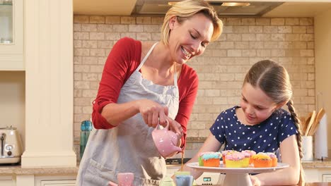 Smiling-daughter-looking-at-her-mother-while-pouring-tea-4K-4k