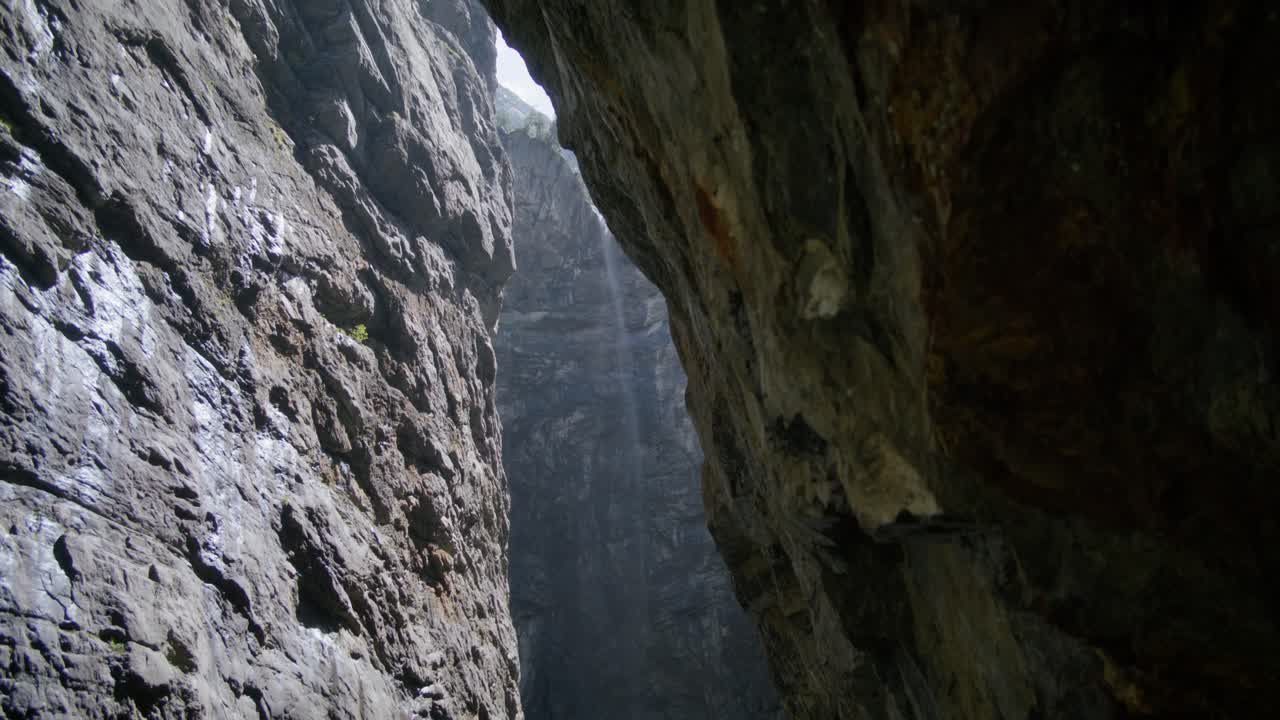 mirando hacia arriba desde la parte oscura de la cueva a las rocas brillantes de la ladera de la montaña | grindelwald suiza cueva en el cañón del glaciar, europa, 4k