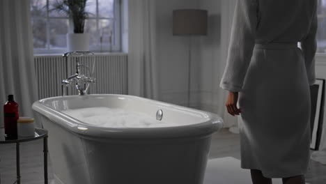 unknown lady walking bathroom closeup. satisfied woman touching bathtub foam