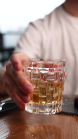 man holding a glass of whiskey at restaurant