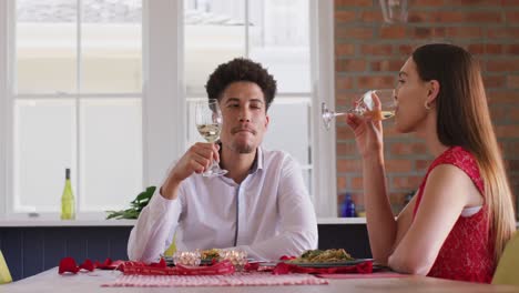 Happy-biracial-couple-having-valentine's-day-celebration-meal-at-home