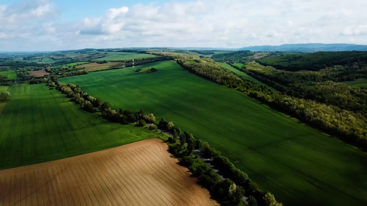 Aerial landscape slideling shot of cloudy bright and shady view of agricultural areas hills and little forest summer zala county hungary europe