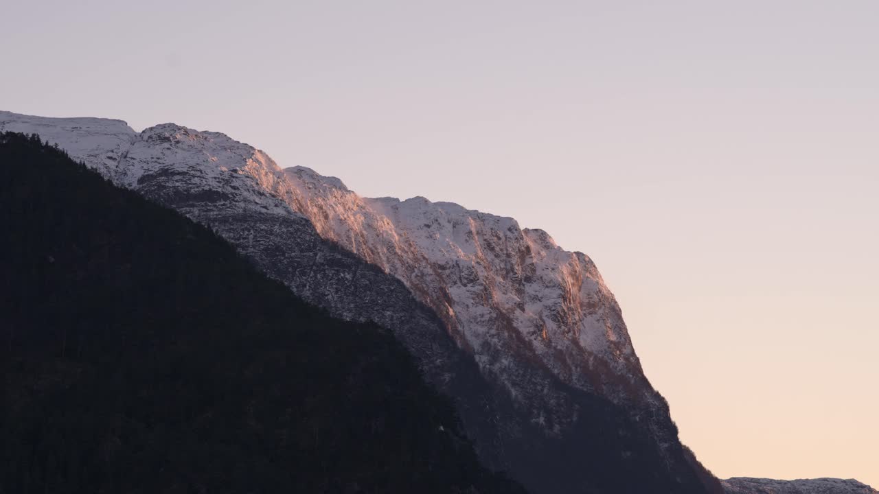 Solnedgang i skumringen og kraftig vind over sneklædte bjergtinder - Time-lapse.