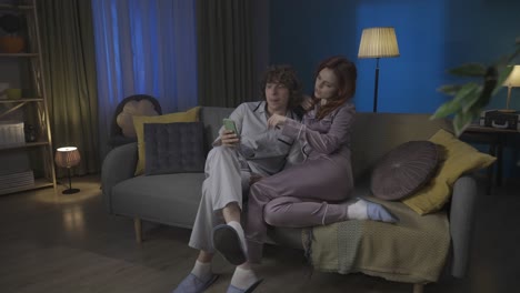 couple watching a video on a smartphone on a couch