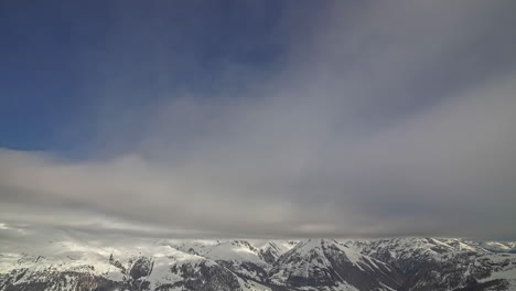 Cloudscape-time-lapse-over-scenic-mountain-range-snow-covered-peaks---puffy-white-clouds-flying-through-blue-sky