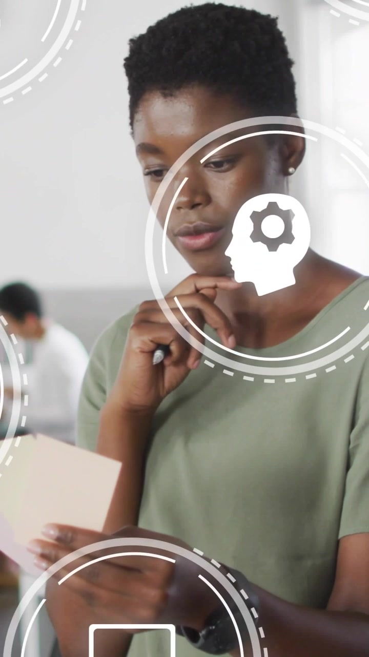 Vertical video: Woman reading card and flipping page, HUD icons circling and illustrating learning