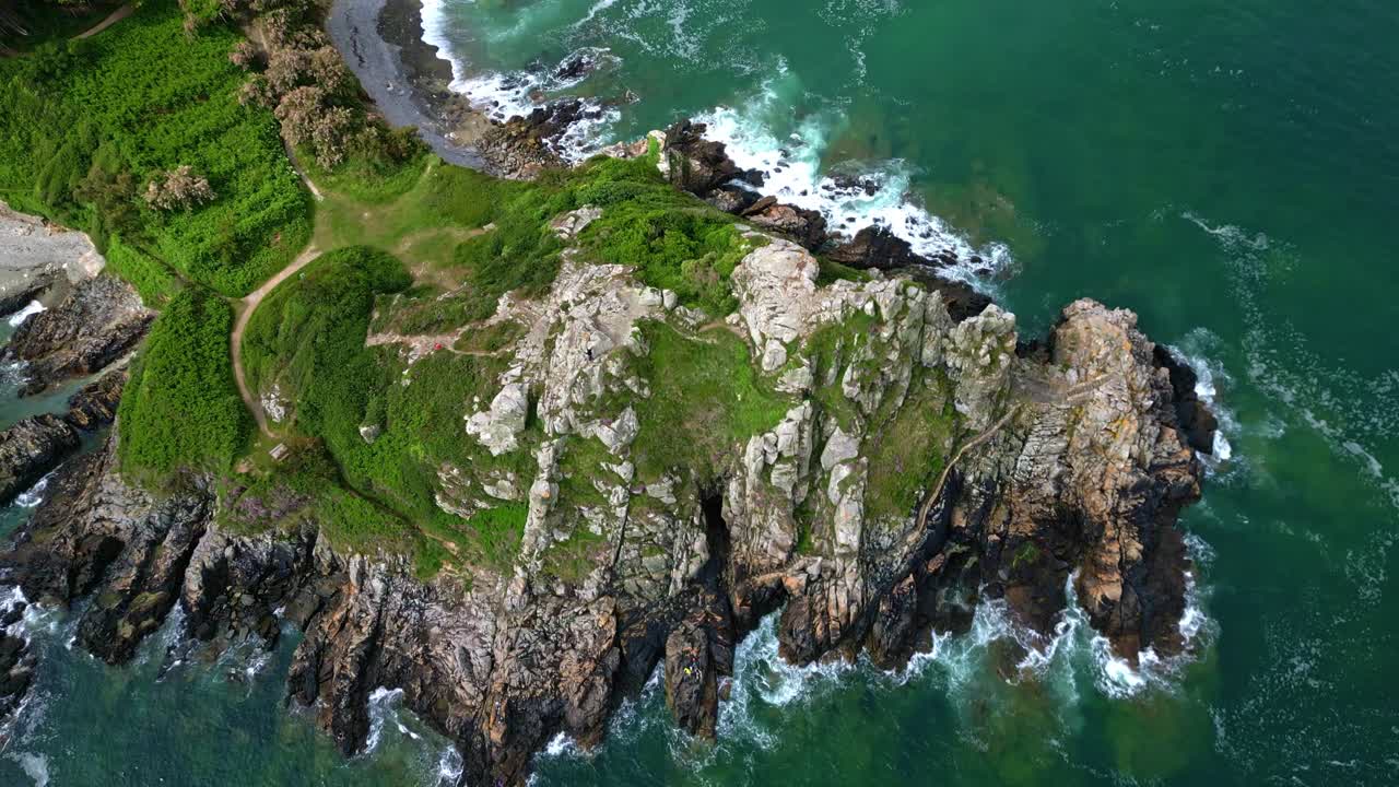 Top-down drone movement over the jagged Breton cliffs Pointe du Chateau at Trestrignel beach, Perros-Guirec, Brittany, France.