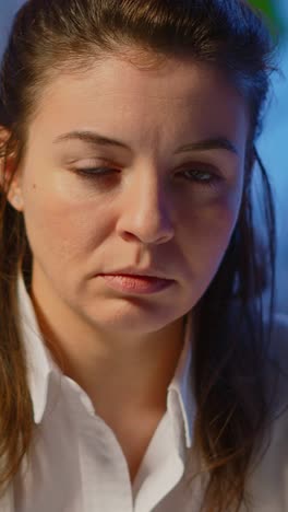 vertical video: close up of overworked business woman looking exhausted at camera