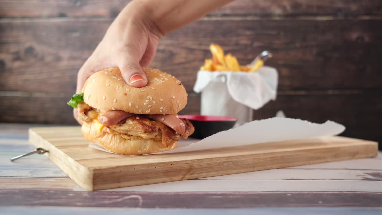 mano sosteniendo una deliciosa hamburguesa de pollo con papas fritas