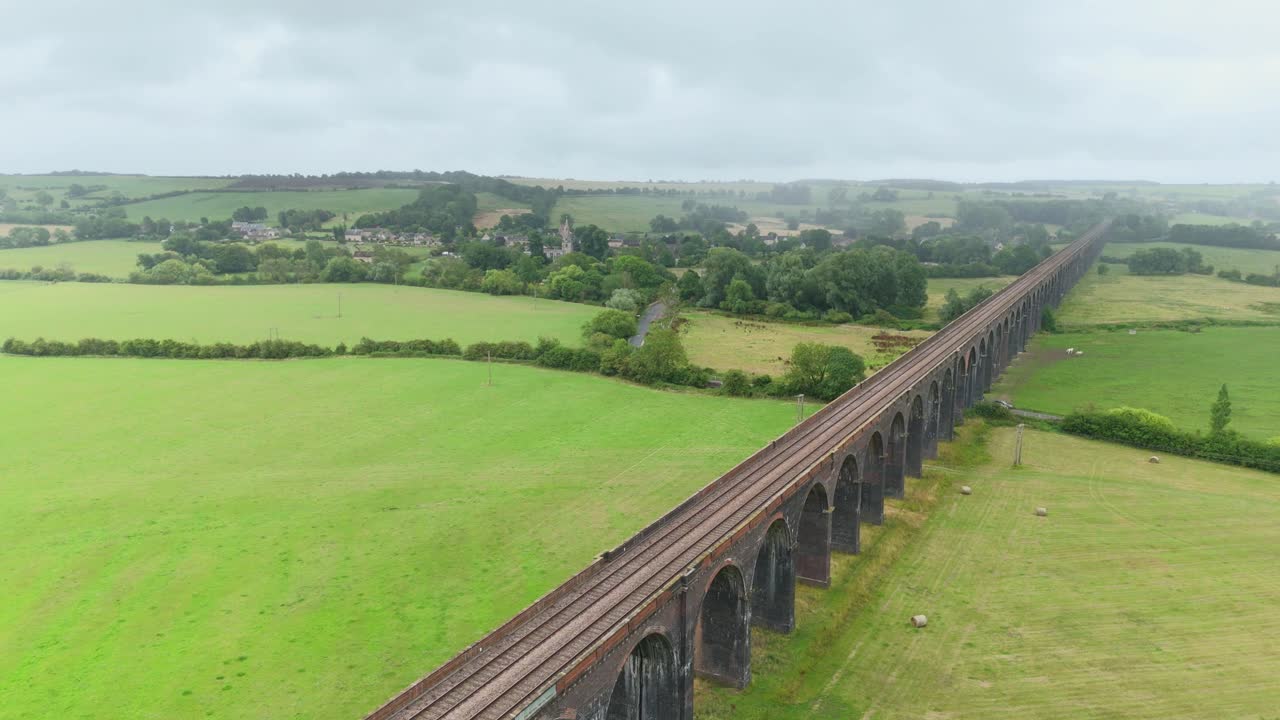 Aerial drone cinematic footage of Harringworth Viaduct railway bridge with many arches spanning green wetland farmland near Corby England UK