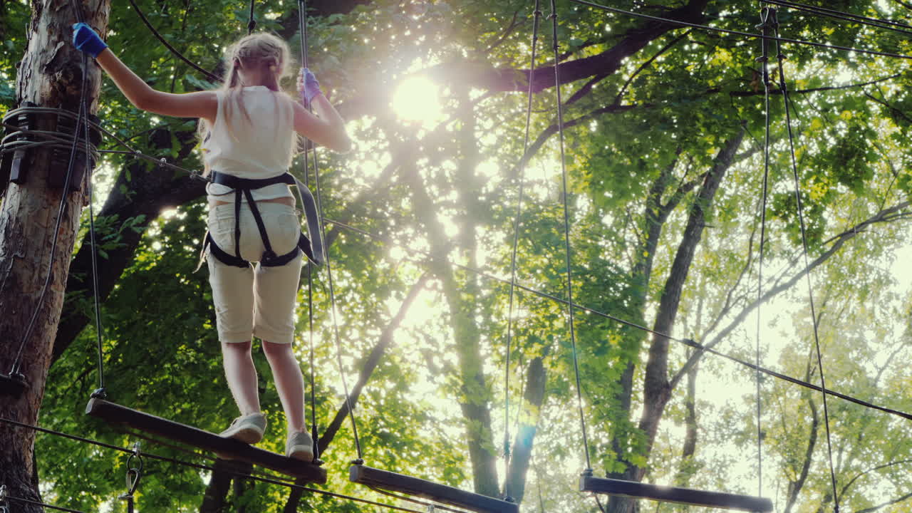 용감한 아이가 키 큰 나무 사이의 줄타기를 따라 걷는다 활동적인 어린 시절과 재미