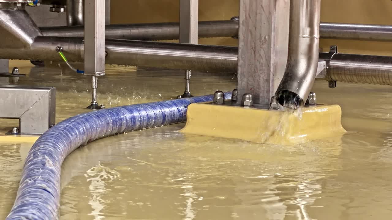 L'acqua scende a cascata da un tubo metallico in un'area contenuta, circondata da tubazioni industriali. Utile per presentazioni di ingegneria o studi sulla gestione dell'acqua.