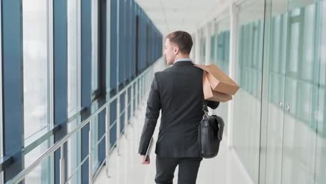 Rear-view,-Stylish-young-man-walking-down-the-mall-with-shopping-bags