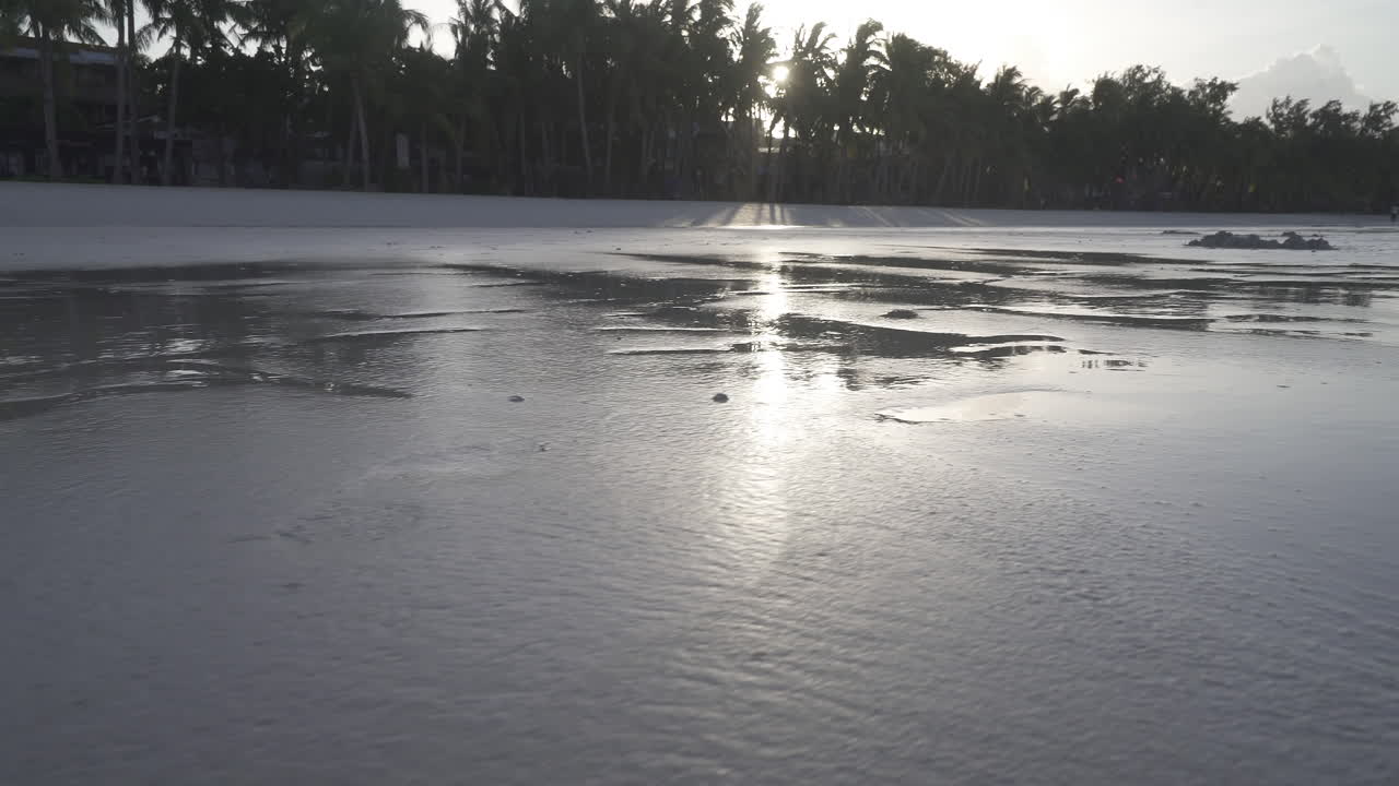 Low Angle Shot Of Water Spots And Reflections Along The Clean White Beach Of Boracay Island