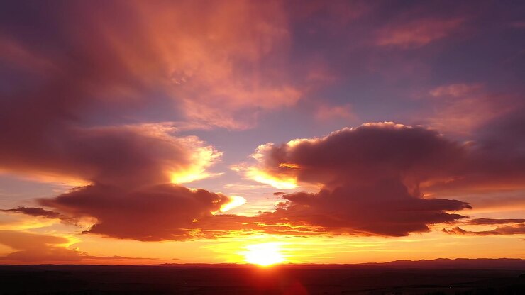 Nuvole dorate e drammatiche e un cielo arancione vibrante durante il tramonto
