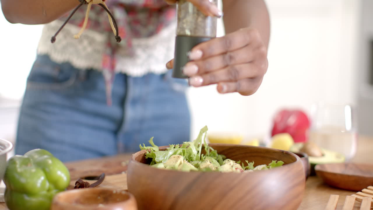 Condendo un'insalata fresca, una donna prepara un pasto sano in una ciotola di legno in cucina.