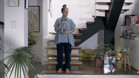 beautiful woman dancing with a water bottle inside her house, a water glass bottle, stairs, concept, art